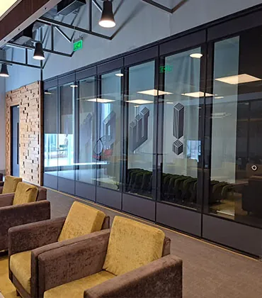 Modular glass office partition wall with black aluminum framing systems.