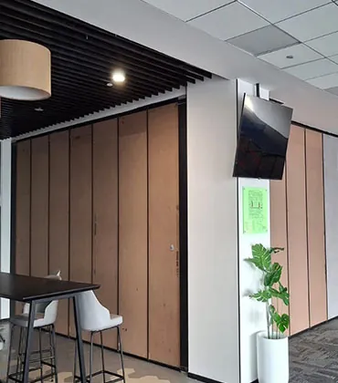 Vertical wooden folding partition wall installed in modern office space.